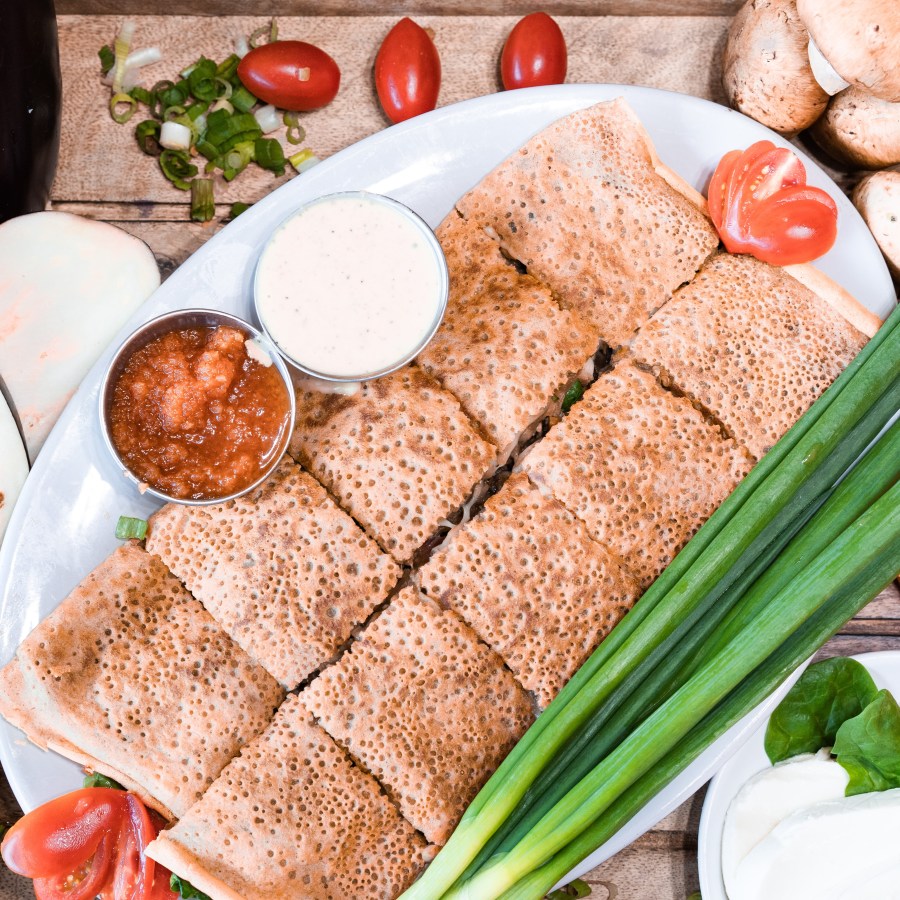 Savory crepes served with dipping sauces and fresh vegetables
